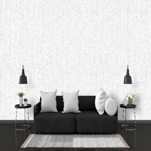 Modern living room with a black sofa, white pillows, and decorative items against a white wall.
