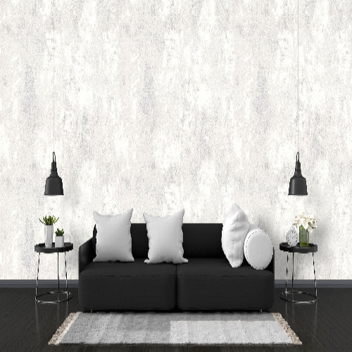 Modern living room with a black sofa, white pillows, and decorative items against a white marble wall.