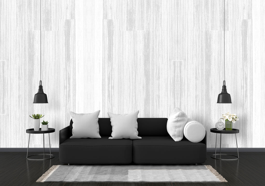Modern living room with a black sofa, white cushions, and decorative items against a striped wall.