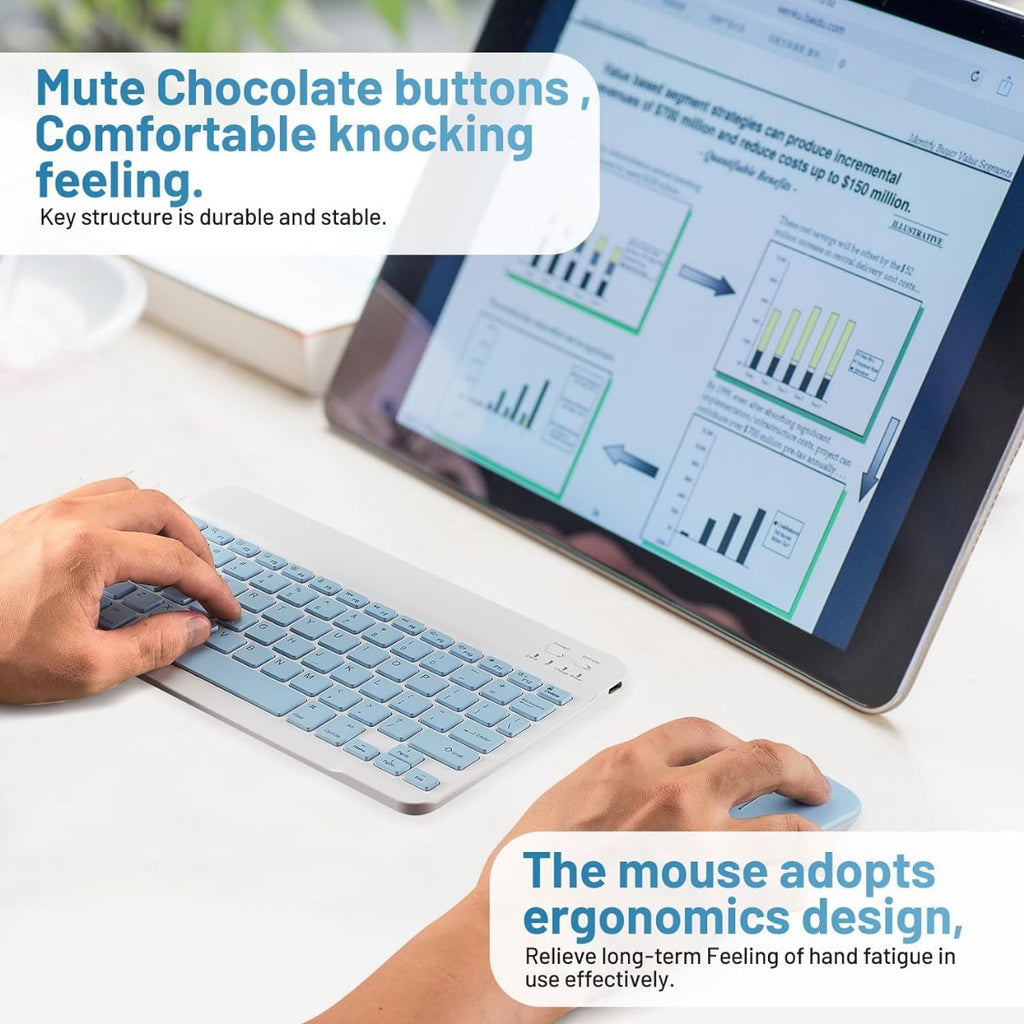 The keyboard is being used to type, and the mouse is held in the hand. In the background, a tablet displays a business chart, suggesting a work or productivity setting.