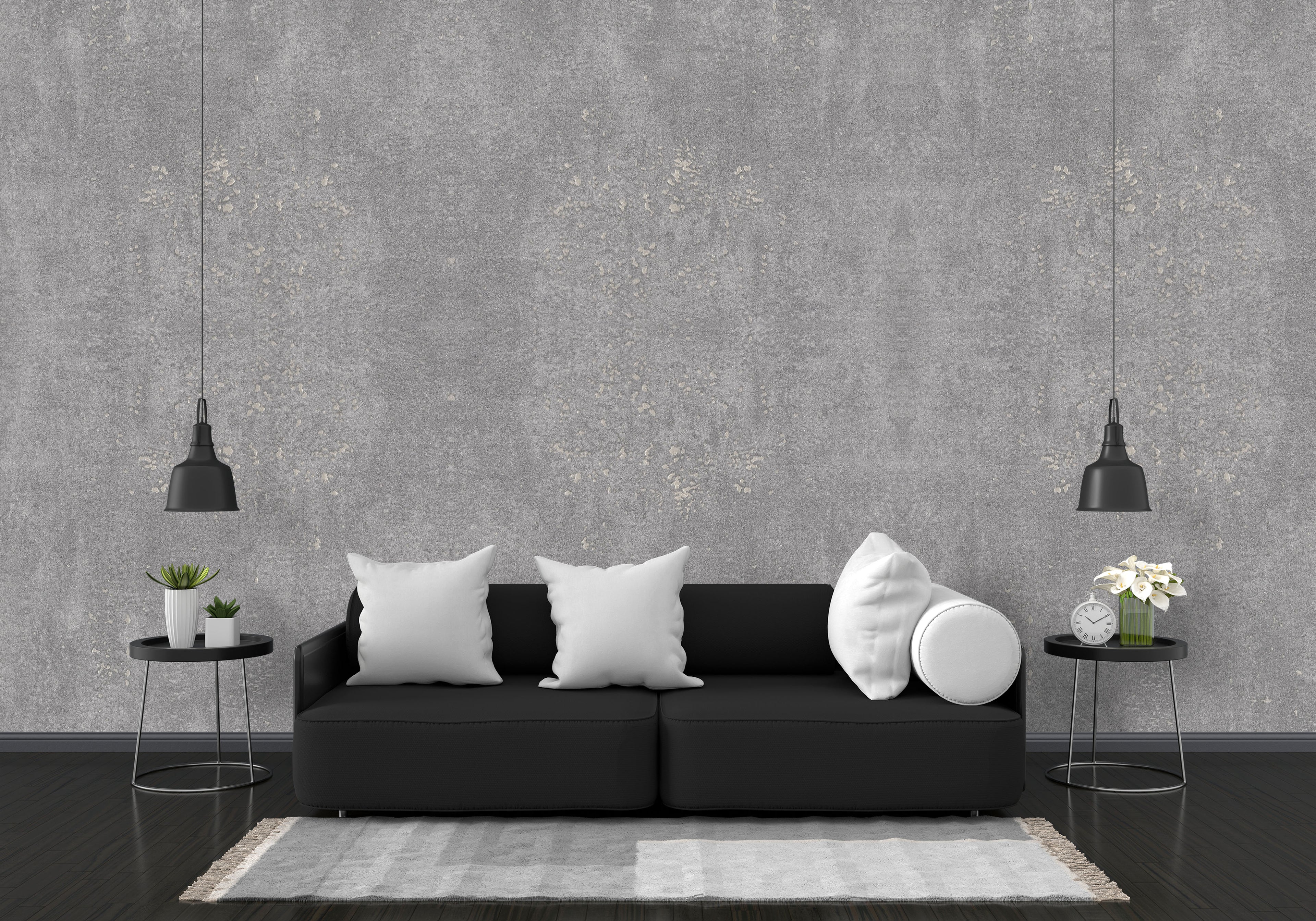 Modern living room with a black sofa, white pillows, and decorative items against a gray concrete wall.