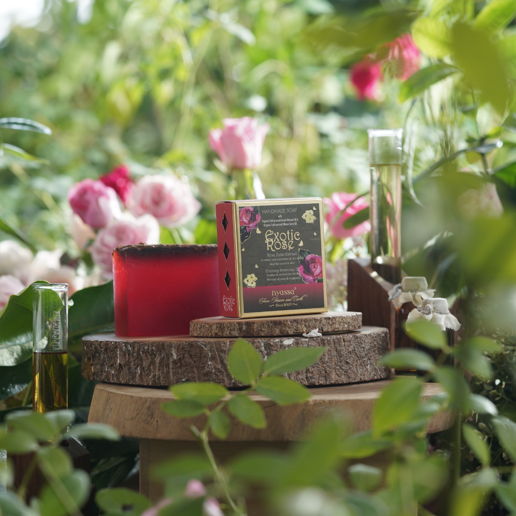 Candle and packaging on a wooden stand with flowers and greenery in the background